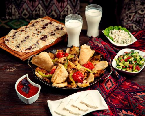 una tavola con un piatto di cibo e del latte di Shafran B&B a Bukhara