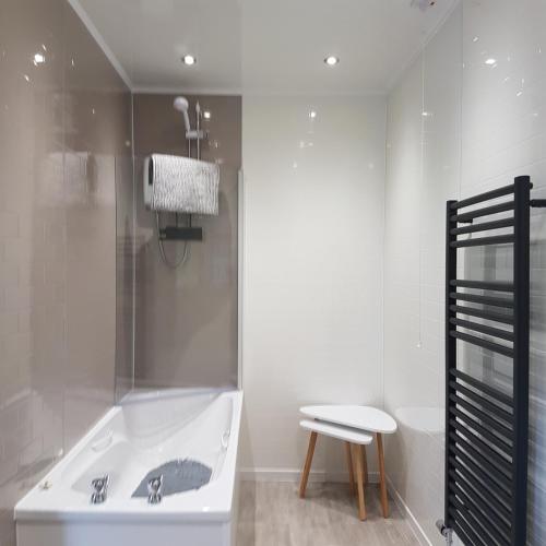 a bathroom with a tub and a toilet and a stool at Beech House in Fort William