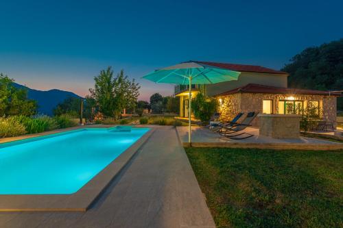 a swimming pool with an umbrella next to a house at Villa Luce in Omiš
