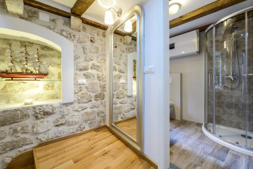 a bathroom with a stone wall and a glass shower at Alberto Apartment in Dubrovnik
