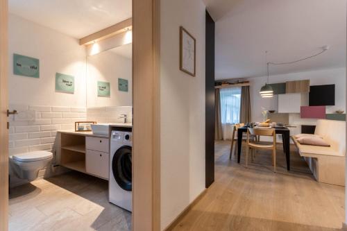 a bathroom with a washer and dryer next to a kitchen at Die Alte Gerberei - La Vecchia Conceria OG1 in Monguelfo