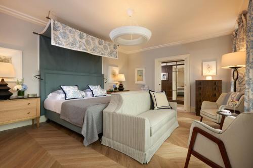 a bedroom with a bed and a couch and a chair at Rocco Forte Hotel De Russie in Rome