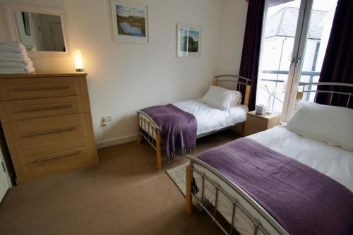 a bedroom with two beds and a dresser and a window at Penthouse Apartment in Stirling