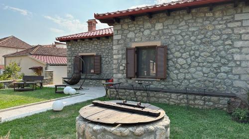 a stone house with a wooden table in the yard at Guesthouse Pyxari in Kalabaka