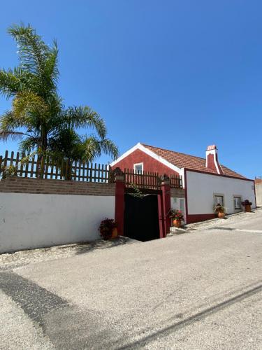 une maison rouge et blanche avec un portail et un palmier dans l'établissement Páteo do Duque, à Salir de Matos