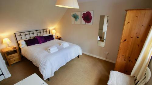 a bedroom with a large white bed with purple pillows at View Cottage in Lochearnhead