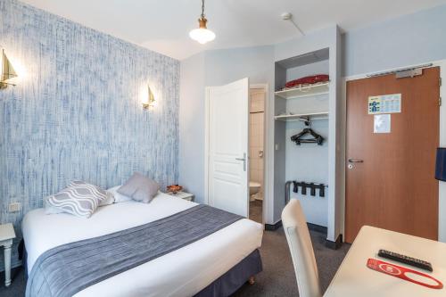 a small bedroom with a bed and a desk at Hotel des Ducs in Alençon