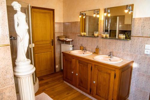 uma casa de banho com dois lavatórios e uma estátua em Gite la vigne 4 à 10 personnes Domaine Saint Raphaël em Prats-de-Carlux