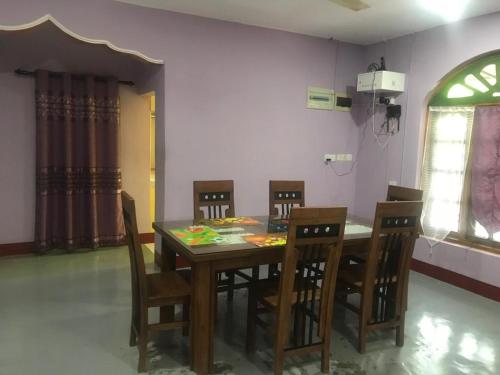 uma sala de jantar com uma mesa de madeira e cadeiras em MSV Villa résidence home em Batticaloa