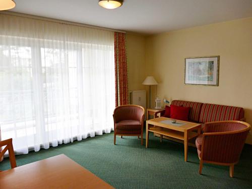 アールベックにあるFerienwohnung 1 2 12 Inselstrandのソファ、椅子、テーブルが備わるホテルルームです。