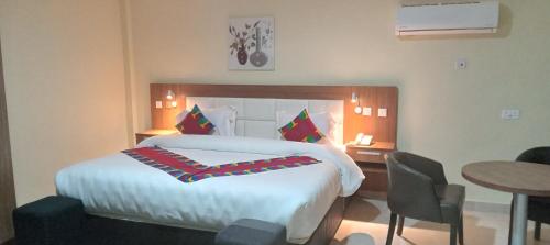 ein Hotelzimmer mit einem großen Bett und einem Tisch in der Unterkunft RHOGEM Hotel in Takoradi