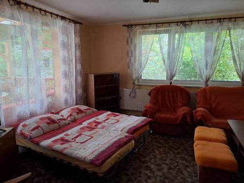 a bedroom with a bed and two chairs and windows at Zdeňka in Vracov