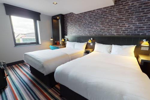 a hotel room with two beds and a brick wall at Village Hotel Glasgow in Glasgow