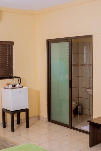 a bathroom with a glass door and a toilet at Road House Guest House in Omuthiya
