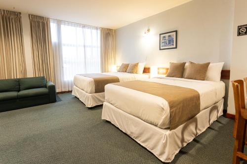 a hotel room with two beds and a couch at Apartotel Tairona in San Pedro