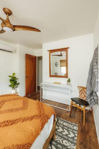 a bedroom with a bed and a mirror and a chair at The Kumu House in Kailua-Kona