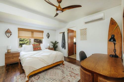 a bedroom with a bed and a desk and a ceiling fan at The Kumu House in Kailua-Kona