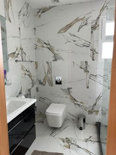 a white bathroom with a toilet and a sink at Villa Rêve d'Agadir - Piscine Founty - Parking - Confort et Spacieuse villa familliale privée in Agadir
