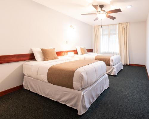 a hotel room with two beds and a ceiling fan at Apartotel Tairona in San Pedro