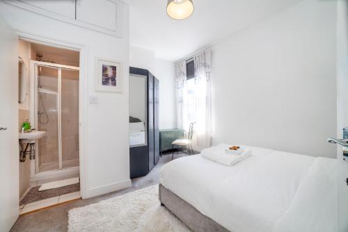 Habitación blanca con cama y baño. en Amazing 2BDR apt near park, Herne Hill, en Londres