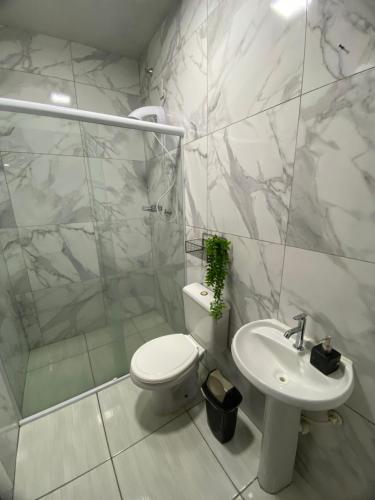 a white bathroom with a toilet and a sink at Pousada Brunetti in Penha