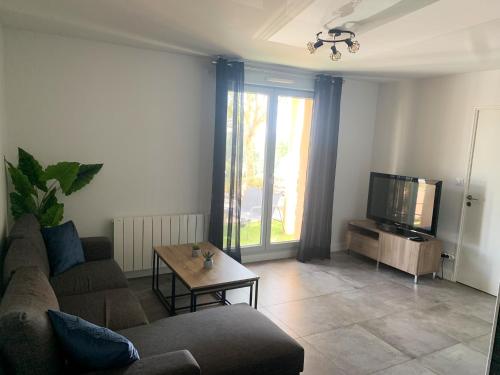 un salon avec un canapé et une télévision dans l'établissement Appartement Les Hauts du Beaujolais, à Limas