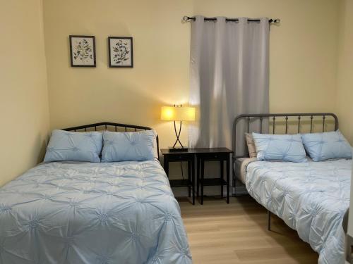 une chambre avec deux lits et une table avec une lampe dans l'établissement Victoria Family Vacation Home - King Bed Private Yard BBQ Deck Gazebo - 4 Minutes To The Falls, à Niagara Falls