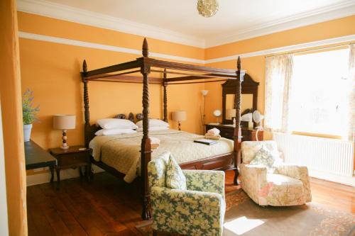 ブロムヤードにあるHuntlands Farm Bed & Breakfastのベッドルーム1室(天蓋付きベッド1台、椅子2脚付)