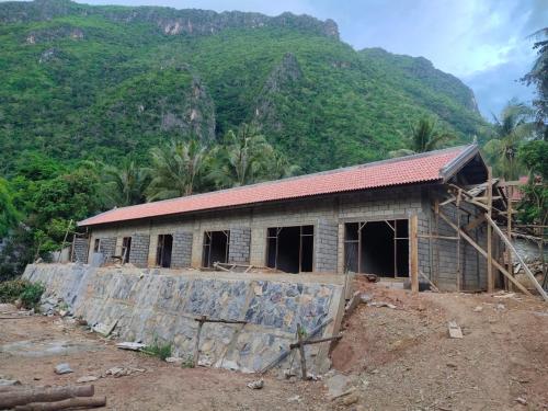 un edificio en construcción frente a una montaña en My Nongkhiaw, en Nongkhiaw