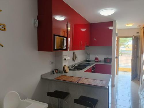 a kitchen with red cabinets and a counter with stools at Villa Costa Antigua in Costa de Antigua