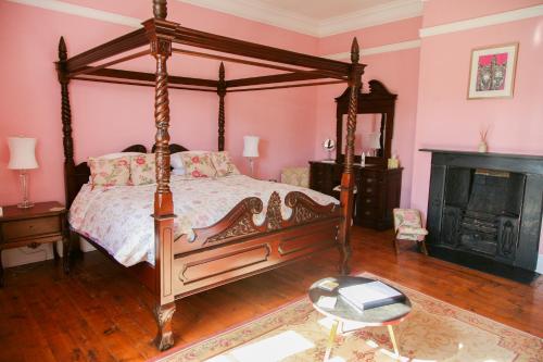 a bedroom with a canopy bed and a fireplace at Huntlands Farm Bed & Breakfast in Bromyard