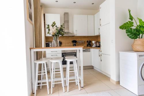 a kitchen with white cabinets and bar stools at Garden Apartment, Close to Schönbrunn in Vienna