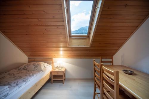 um quarto com uma cama, uma mesa e uma janela em Apartmaji Colja em Bohinj