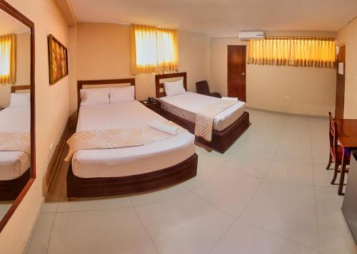 a hotel room with two beds and a table at Hotel America Pucallpa in Pucallpa
