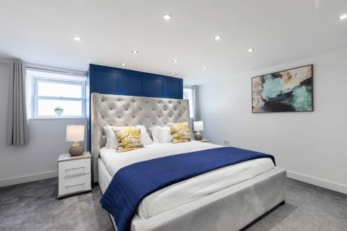 a bedroom with a large bed with a blue headboard at Prestbury Road in Cheltenham