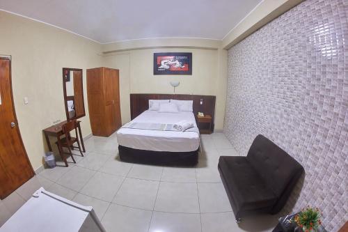 a bedroom with a bed and a chair in it at Hotel America Pucallpa in Pucallpa