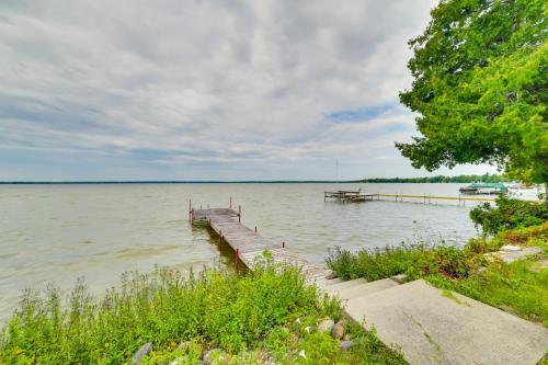 a dock on a lake with a boat in the water at Lakefront Michigan Abode with Deck and Fire Pit! in Cheboygan
