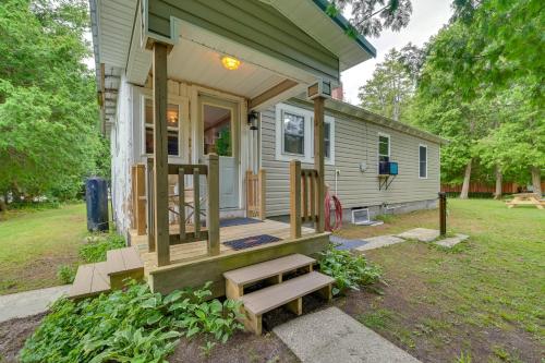 a tiny house with a porch and a bench at Lakefront Michigan Abode with Deck and Fire Pit! in Cheboygan