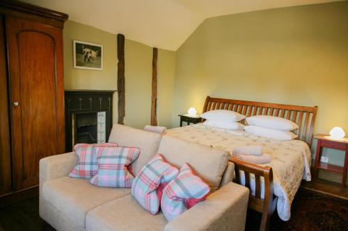 a bedroom with a bed and a couch with pillows at Huntlands Farm Bed & Breakfast in Bromyard