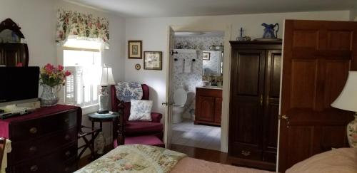 a bedroom with a bed and a chair and a mirror at Eastgate Inn B&B in Lenox