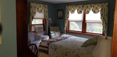 a bedroom with a bed and two windows at Eastgate Inn B&B in Lenox