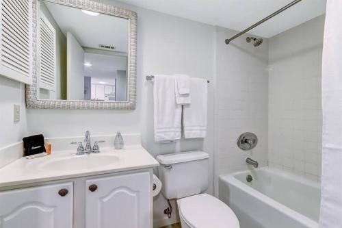 a white bathroom with a sink and a toilet and a mirror at Unobstructed Oceanfront Views in Gated Community-2 Pools-Surf & Racquet B123 in Fernandina Beach
