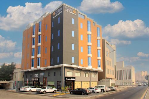een hoog gebouw met auto's geparkeerd op een parkeerplaats bij Swat Hotel Apartments 4 in Al Khobar