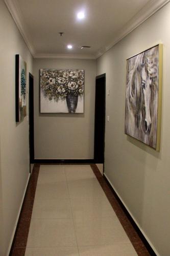 a hallway with two paintings on the walls and a hallway with a hallway at شقق سوات للشقق المخدومة 4 in Al Khobar