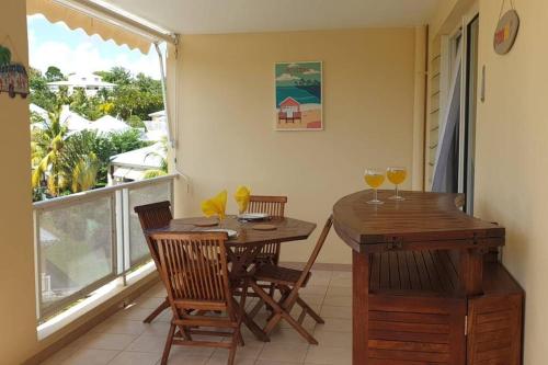 a dining room with a table and two glasses of wine at Appartement O Ti Kolibri, cosy et idéalement situé in Sainte-Luce