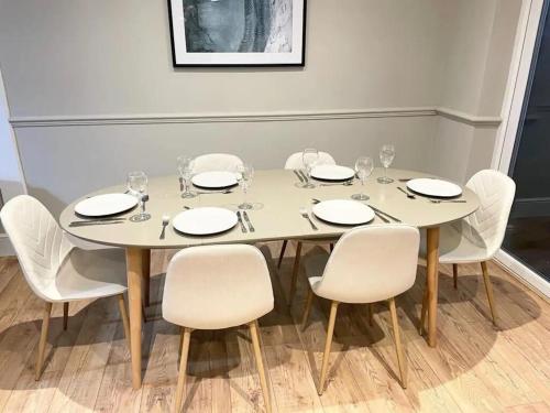una mesa blanca con sillas blancas y gafas. en Comfortable 5-Bedroom House in Cheltenham, en Cheltenham