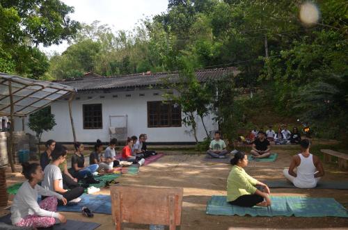 un grupo de personas sentadas en esteras frente a una casa en Spiritual Nature Farm - Sri Lanka, en Matale