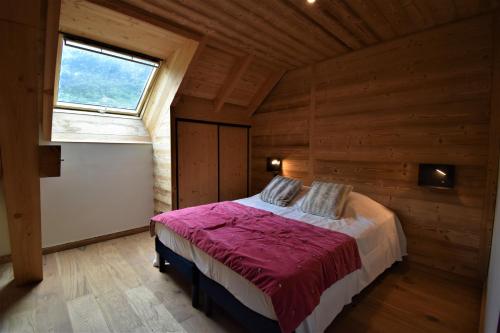 een slaapkamer met een bed in een kamer met een raam bij VAUJANYLOCATIONS - Sertetsagne in Vaujany