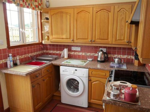 a kitchen with a washing machine in a kitchen at Branta Cottage in Dumfries