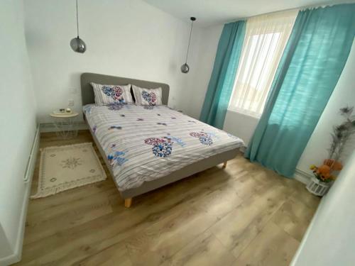 een slaapkamer met een bed met blauwe gordijnen en een raam bij Alin's home in Ocna-Mureşului